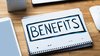 Foto eines Schreibtischs mit aufgeklapptem kariertem Notizbuch. Auf dem Notizbuch steht groß das Wort „BENEFITS“. Daneben sind Laptop, Tablet und Computermaus zu sehen. Das Bild steht für die Vorteile und Zusatzleistungen bei Husemann & Fritz.