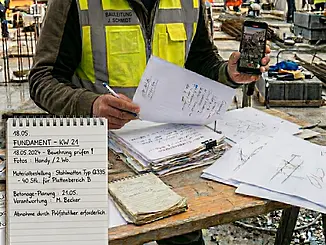 Bauleiter mit Tablet und Baustellenunterlagen bei der digitalen Dokumentation und Organisation auf der Baustelle
