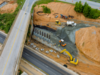 Bauingenieure und Fachkräfte auf einer Brückenbaustelle steuern ein komplexes Ingenieurbauprojekt digital mit Tablet und mobiler Software.