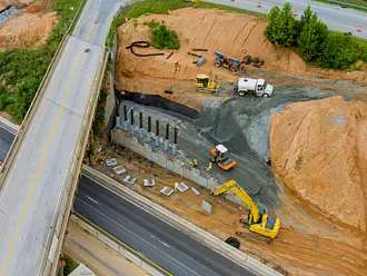 Bauingenieure auf einer Brückenbaustelle nutzen Tablet und mobile Ingenieurbau-Software zur digitalen Projektsteuerung.